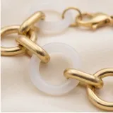 Pulsera de eslabones alternados, combinando eslabones circulares de metal dorado con eslabones circulares de cerámica blanca.