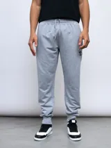 Pantalón de jogging gris melange con puños ajustados en los tobillos y cordón en la cintura. Presenta el logo Umbro bordado en negro en la pierna izquierda.