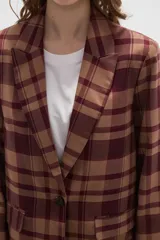 Blazer de corte holgado con diseño a cuadros en tonos marrones y negros. Presenta cuello con solapa, cierre frontal con un botón y bolsillos laterales con solapa.