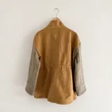 Chaqueta de silueta relajada, confeccionada en paño de lana color verde militar con detalles en pana de algodón marrón en el cuello y los bolsillos. Cuenta con cuello alto, bolsillos frontales amplios y cordón regulable en la cintura.