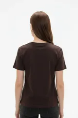 Remera de algodón negra de manga corta y cuello redondo, con estampa frontal que incluye letras rojas y gráficos en tonos dorados.