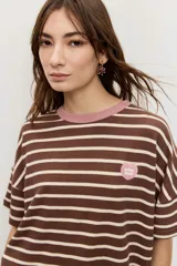 Remera de manga corta con diseño a rayas horizontales azules y blancas, cuello redondo en color tostado y parche bordado en el pecho.