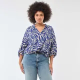 Blusa de manga larga con estampado abstracto en tonos azul y beige, cuello en pico y diseño holgado con puños elásticos.