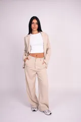 Pantalón de vestir beige con pinzas, tiro alto y perneras amplias de corte recto.
