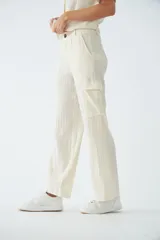 Pantalón cargo de tiro alto y corte recto, confeccionado en viscosa con textura arrugada. Cuenta con bolsillos laterales, cierre de cremallera y botones, y presillas para cinturón.