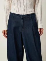 Pantalón slouchy de denim azul oscuro con pinzas en la cintura, bolsillos laterales y puños fruncidos con elástico en los tobillos.