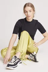 Pantalón de vestir color verde oliva, de corte ancho y tiro alto, con bolsillos laterales tipo cargo y detalle de pinzas en la cintura.