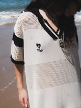 Remerón tejido de punto color azul marino con calados, cuello estilo camisa en verde oscuro con rayas blancas y verdes, y logo bordado en blanco en el pecho.