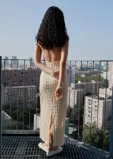 Vestido largo de diseño entallado con cuello halter y espalda descubierta. Confeccionado en tejido de crepé con textura, presenta tirantes finos y cierre de nudo en el cuello.