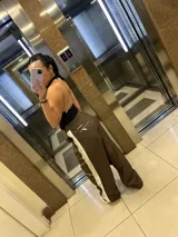Pantalon de estilo deportivo color marron con paneles laterales en color crema y detalles de costuras blancas. Presenta cintura elastizada con cordón de ajuste y corte holgado.