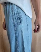 Pantalón de algodón color arena, de corte recto y holgado, con cintura elástica y detalle de costuras horizontales decorativas en la parte inferior de las piernas.