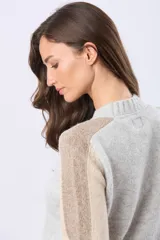 Buzo tejido de abrigo en color gris con mangas en combinación de tonos beige y tostado. Presenta cuello redondo y detalles de textura acanalada en puños y cuello.