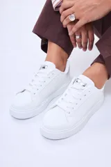 Champion de plataforma color blanco, con cordones al tono y detalle metálico plateado en la lengüeta y el talón.