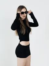 Camiseta negra de tejido texturizado, con cuello alto y mangas largas ajustadas.