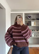 Buzo de tejido de punto grueso con diseño de rayas horizontales en color marrón y rosado, cuello alto y mangas largas abullonadas.