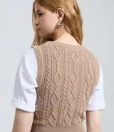 Chaleco corto de punto color beige, con escote cuadrado, breteles anchos y diseño texturizado con trenzas verticales.