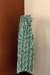 Pantalón de algodón con cintura elástica y cordón ajustable. Presenta un diseño de rayas verticales verdes sobre fondo blanco, con un estampado lineal de pequeñas flores rojas a lo largo de las rayas.
