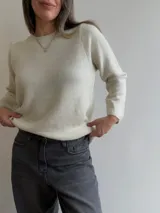Sweater de punto de corte holgado y diseño minimalista, con cuello redondo y mangas largas. Presenta una textura suave y un largo que llega por debajo de la cadera.