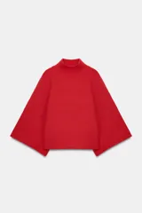 Jersey de punto liso color rojo, con cuello subido y mangas anchas acampanadas. Presenta acabados en rib en cuello, puños y ruedo.