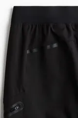 Pantalón de jogging deportivo negro de corte ajustado, confeccionado en tejido funcional DryMove™ que absorbe el sudor. Cuenta con cintura elástica con cordón de ajuste, bolsillos laterales, bolsillos con cierre en las piernas y bajos elásticos.