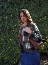 Chaqueta corta con estampado a cuadros en tonos negro, gris y marrón, con ribetes en marrón y cierre frontal con lazos.