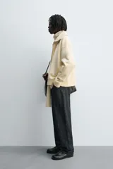 Sudadera color crema de algodón con interior afelpado, corte relajado, cuello subido y manga larga. Presenta bolsillos de vivo en la cadera y acabados en rib, con cierre frontal de cremallera.