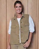 Chaleco de gabardina color tostado, con cuello camisero, cierre frontal con botones metálicos y dos bolsillos frontales con solapa.