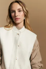 Chaleco de paño color marrón oscuro, de silueta recta y diseño minimalista. Presenta cuello a la base, cierre frontal con botones claros y bolsillos aplicados.