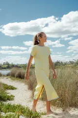 Vestido midi amarillo con cuello y mangas con terminación en celeste. Posee aberturas laterales.