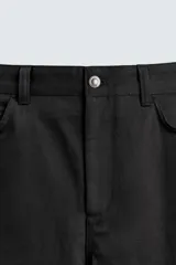 Pantalón relaxed fit negro confeccionado en tejido de algodón con estructura diagonal, estilo de cinco bolsillos y cierre frontal con cremallera y botón metálico.