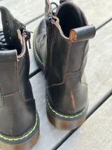 Bota corta de cuero color chocolate, con cordones amarillos y cierre lateral.