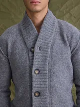 Cardigan de punto gris con cuello tipo chal y cierre frontal de botones. Presenta puños y ruedo acanalados, ofreciendo un diseño clásico y versátil.