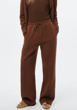 Pantalón de corte recto y holgado, color blanco, con cintura elástica y cordón ajustable. Presenta costuras verticales frontales que estilizan la silueta.