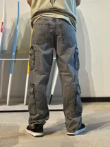 Jean baggy cargo color gris gastado, con tiro alto, piernas anchas y múltiples bolsillos laterales funcionales.