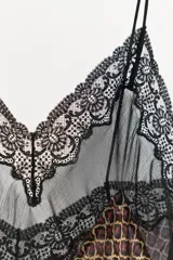 Vestido corto asimétrico con estampado geométrico en tonos marrones y naranjas. Presenta escote en pico, tirantes finos y detalles de encaje negro en el escote y el bajo.