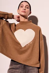 Sweater marrón de algodón peinado con cuello alto y calce oversize. Estampado frontal de corazón blanco con texto en cursiva.