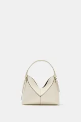 Bolso tipo mini shopper de diseño estructurado en color beige, con forma de V en la parte superior y asa de mano fija. Presenta costuras visibles y detalles metálicos en los laterales.