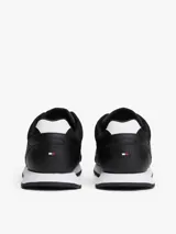 Zapatillas deportivas Tommy Hilfiger de estilo running, confeccionadas en una mezcla de piel y poliuretano. Presentan un diseño de corte bajo con cordones, paneles de texturas mixtas, detalles de ventilación en la parte superior y suela de goma con tacos.