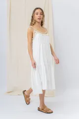 Vestido largo blanco de algodón con escote en V, breteles finos regulables con lazo y borlas, y detalle de tejido artesanal en el escote.