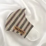 Tapabocas de tela con estampado a rayas verticales en tonos beige, negro y rojo. Tiene elástico blanco para sujetar a las orejas y etiqueta de cuero sintético con la marca Valente.