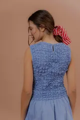 Vestido midi sin mangas de color azul con estampado a cuadros vichy. Presenta la parte superior completamente elastizada y ajustada con efecto fruncido, y falda amplia y suelta.