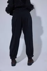 Pantalón tipo bombachita con pinzas que aportan volumen, confeccionado en Tencel. Presenta cierre frontal con botones dorados, bolsillos delanteros y ruedo ajustable mediante botón dorado.