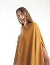 Poncho tejido de punto con diseño asimétrico y aberturas laterales para los brazos.