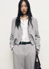 Pantalón de sastreria gris con diseño de raya diplomática, de tiro bajo, corte recto y amplio con pinzas delanteras y trabillas para cinturón.
