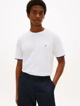Remera blanca de manga corta Tommy Hilfiger, con cuello redondo y ribete azul en los puños. Presenta un pequeño logo bordado en el pecho.
