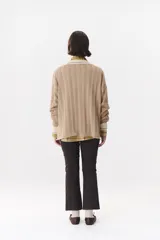 Sweater de punto color marrón con cuello polo en contraste color crema. Presenta diseño de rayas verticales texturizadas, mangas largas con puños en color crema y corte holgado.