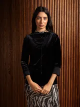 Blusa de terciopelo negro con escote bote y mangas tres cuartos con puños de tela lisa. Presenta un corte al cuerpo y un diseño minimalista.