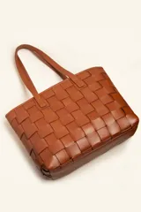 Cartera tipo tote de cuero marrón, confeccionada con diseño trenzado artesanal y doble asa de hombro.