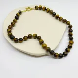 Collar de cuentas esféricas de piedra ojo de tigre de 10 mm, con separadores de nudos de hilo y cierre de mosquetón con baño de oro.