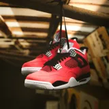 Championes Air Jordan 4 Retro en color rojo con detalles en negro, gris y blanco, confeccionados con paneles de malla y refuerzos plásticos característicos del modelo.